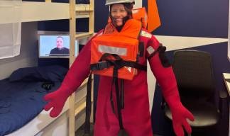 Penny Hogan of Unity Bank dons an immersion suit during a safety drill challenge in the Nautilus ship's cabin stand. Image:Penny Hogan of Unity Bank dons an immersion suit during a safety drill challenge in the Nautilus ship's cabin stand.